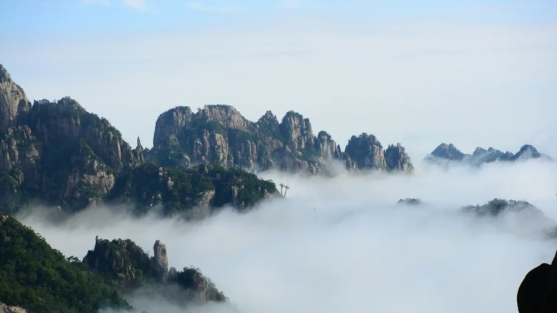 Granite peaks rising out of a sea of cloud, with pines on the ridges