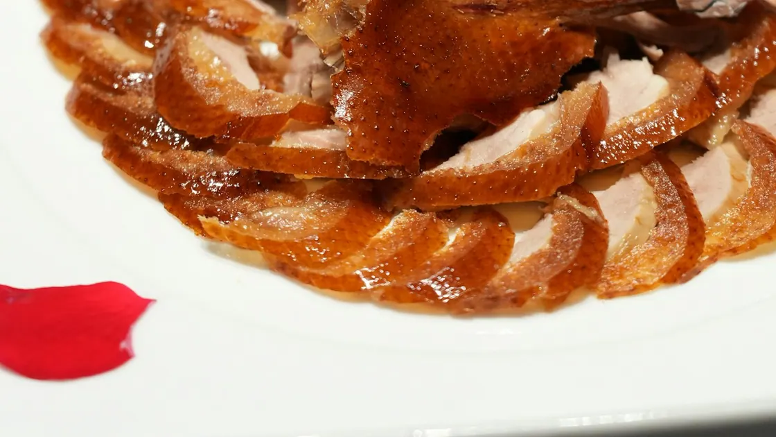 Slices of lacquered roast duck arranged on a white plate