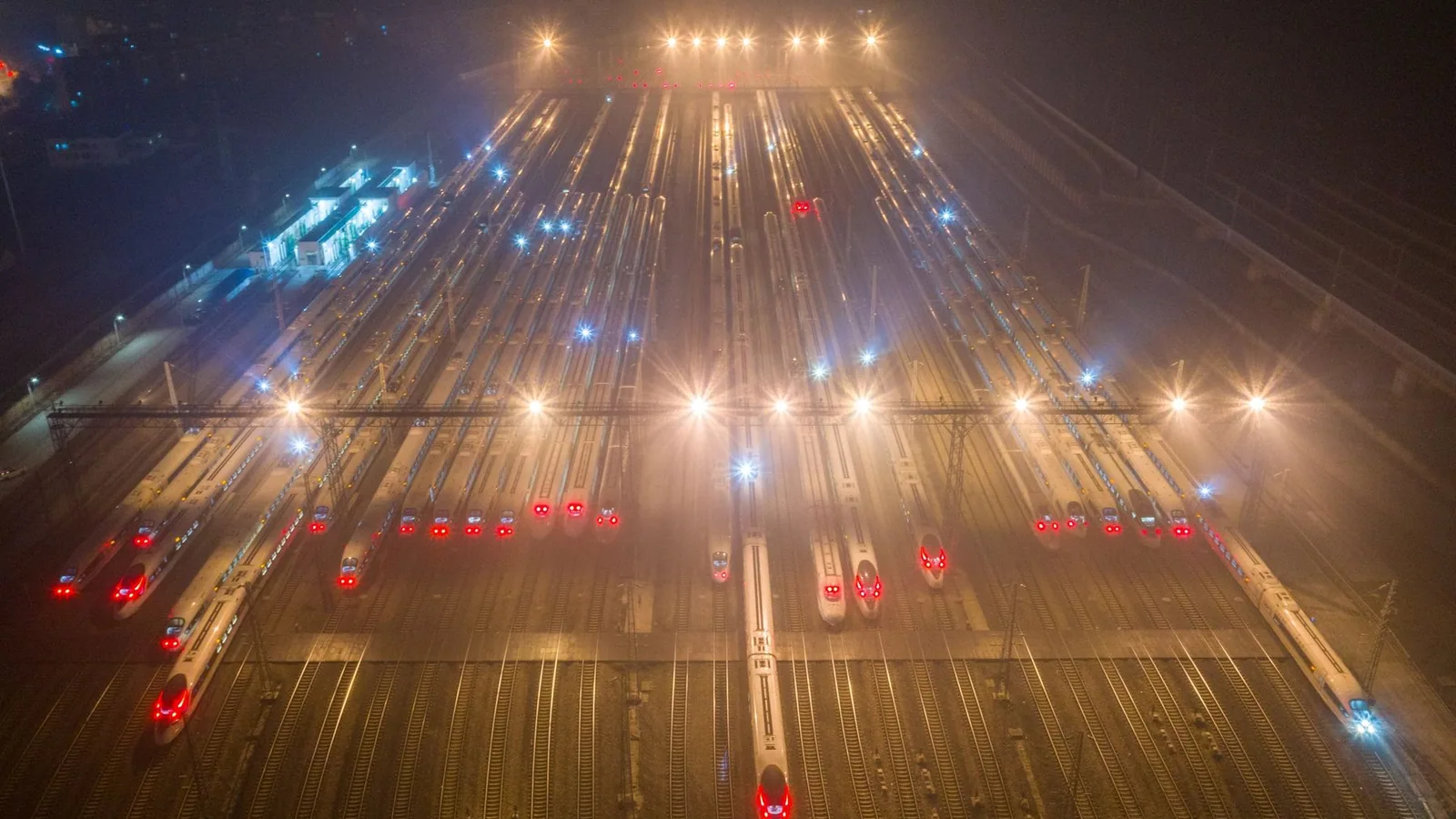 High-speed trains stabled at a rail depot at night.